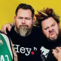 The members of Bowling for Soup pose against a plain yellow background.