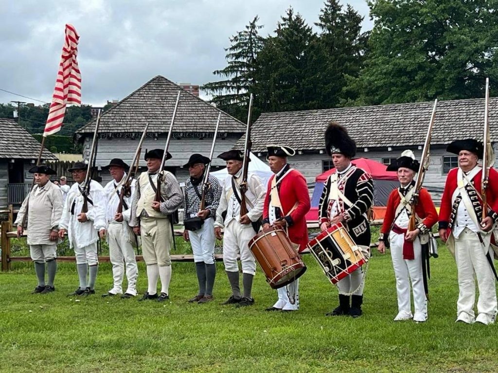 American Revolutionary War reenactors line up for a demonstration outside.