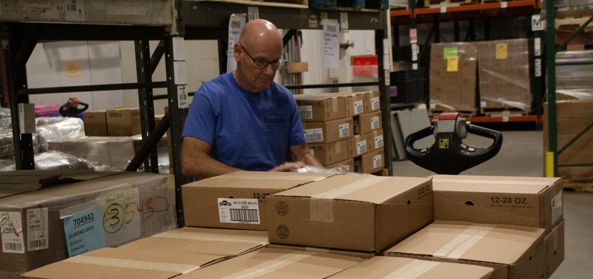 A man in a warehouse loads boxes of food destined for a local food pantry.