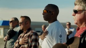 Derrick Wilburn at Freedom Ride Rally in Cortez, Colorado, during pledge. Group shown has hand over hearts