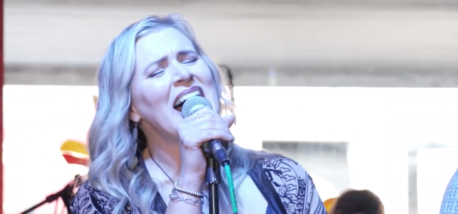 An image of a woman with long blonde hair singing into a microphone.