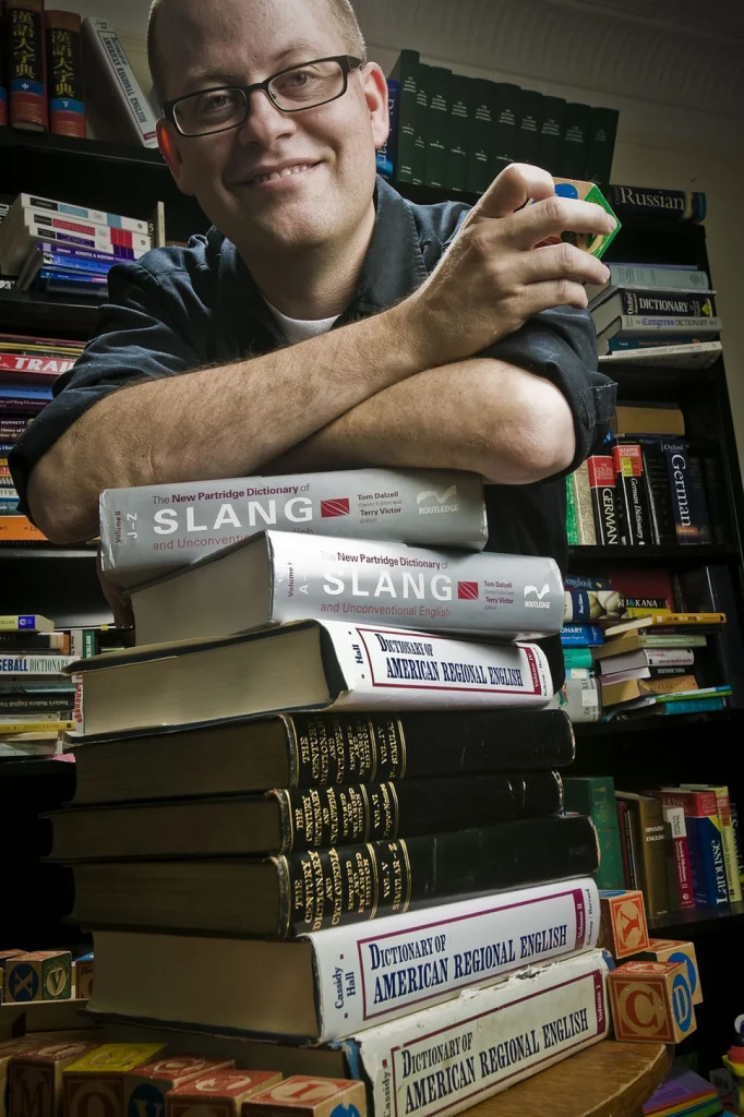 Grant Barrett leans on a stack of books