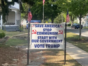 A sign reads Save America Stop Communism Start with our Government Vote Trump