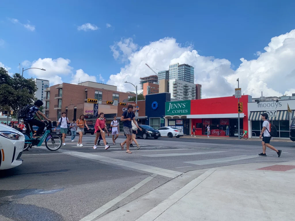 Students at University of Texas in Austin walk across a sidewalk.