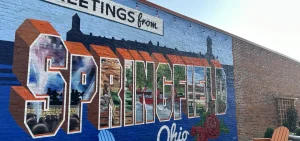 A mural on the side of a building reads "Greetings from Springfield, Ohio"