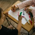 A woman and a child draw in crayon on a piece of paper together