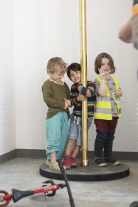 Children stand at one of the brass poles in the news Athens fire station.