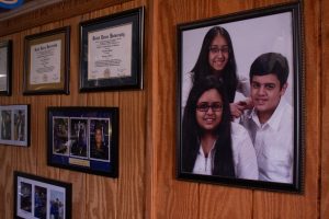 A photo of three siblings hangs next to diplomas and graduation photos.