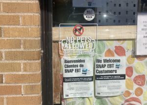 Printouts in a store window tell Spanish and English-speaking visitors that the business accepts EBT cards.