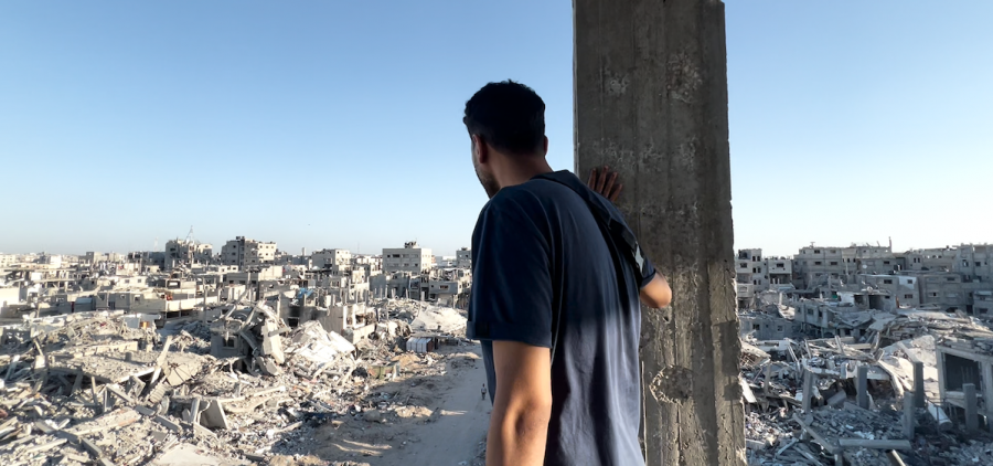 Man leaning on concrete buidling post over looking destroyed concrete city in war between Israelis and Palestinians