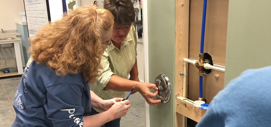 Molly Blair shows Jill Harman how to remove a cartridge from a shower faucet. [David Forster | WOUB]