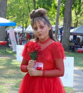 A young woman wears a red dress and holds a bouquet of roses.