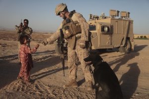 U.S. Marine Corps Cpl. Anthony Marquez, a dog handler with 1st Platoon, Alpha Company, 1st Battalion, 5th Marines, Regimental Combat Team 8, hands an Afghan girl a piece of candy during a vehicle checkpoint in Sangin, Afghanistan, June 17, 2011. The Marines conduct frequent patrols through the area to show a presence and interact with the community to find ways to help the local populace. (U.S. Marine Corps photo by Cpl. Nathan McCord / Released)