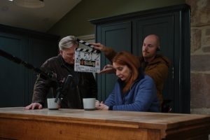 PBS Exclusive Behind the Scenes: Adrian Dunbar as Alex Ridley; Elizabeth Berrington as Jean Dixon. Film clapper/slate between actors.