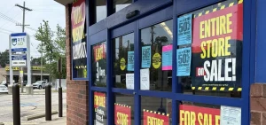 The entrance to a pharmacy is covered with signs indicating an entire store sale.