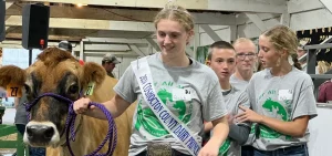 Kenton Wilson walks with a cow and several mentors at Coshocton County's inaugural Ag for All Abilities Livestock Show.