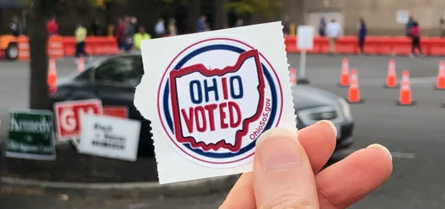 A hand holds up an Ohio voted sticker