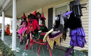 A display of scarecrows is set up on a front porch. 