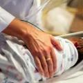 A person comforts a baby in a hospital crib