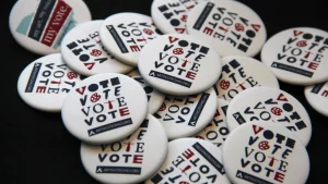 A pile of ArtsVote “vote” buttons sits on a table