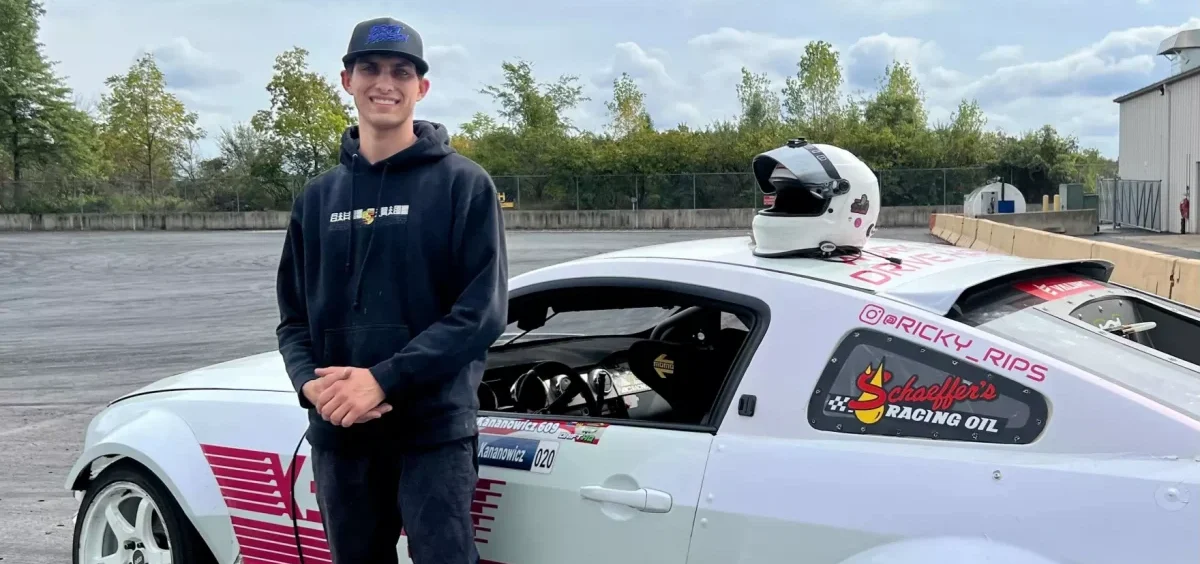 Eric Kananowicz stands posed in front of his white car made for drifting