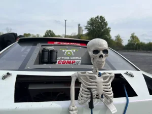 A fake skeleton sits behind a white drifting car