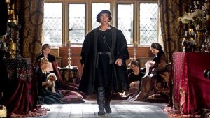 Wolf Hall on Masterpiece. Character walking down middle of room with four women sitting in chairs behind him