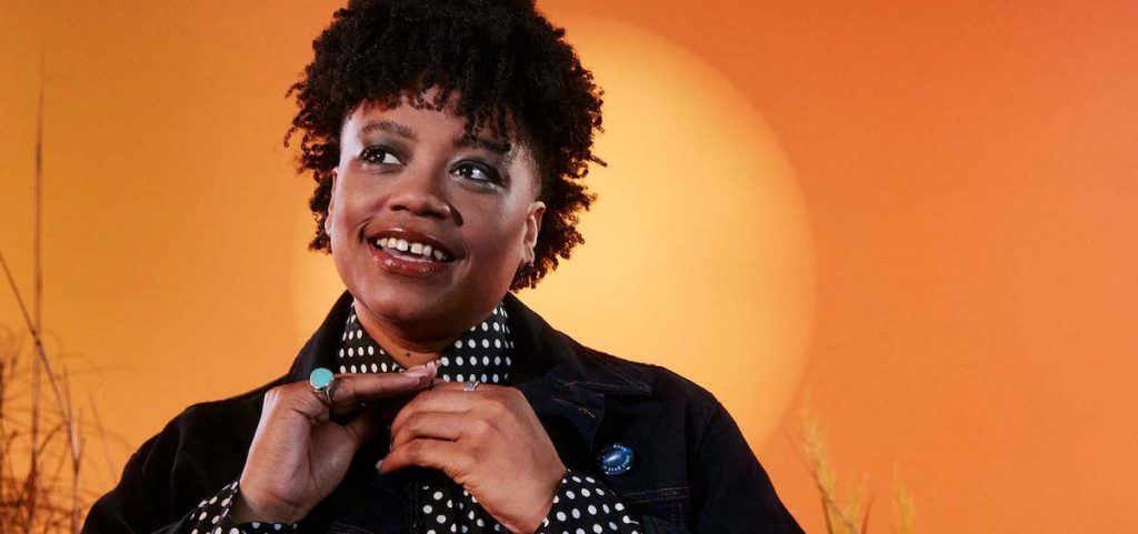 A promotional image of musician Amythyst Kiah against an orange background.