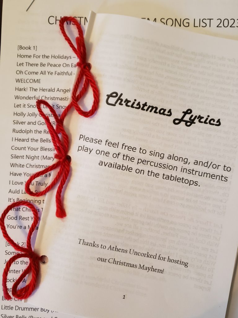 An image of pages tied together with red thread entitled "Christmas Lyrics"