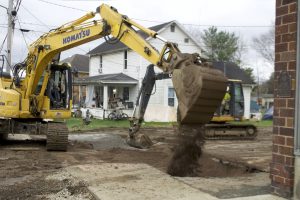 A backhoe operator fills in a hole cut into a street in Chauncey as part of a project to replace all of the village's sewer lines.