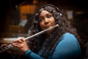 Lizzo wearing headphones and playing flute. Credit: Rahoul Ghose