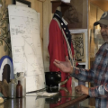 A man wearing a flannel shirt and hat stands in front of an exhibit honoring Black history