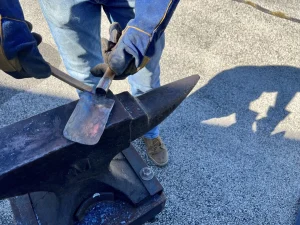 Shenk puts the final touches on a spade that he forged from a shotgun