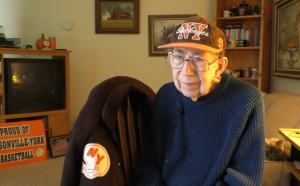 Jack Sowers sits in his living room with a football hat on. 