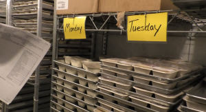 The frozen meals are kept in the Southeast Ohio Food Bank freezer. Packaged food sits under Monday and Tuesday signs in the freezer. 