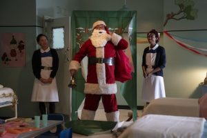 person dressed as Santa Claus with two nurse/midwives next to him