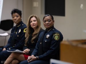 two police officers and a commissioner sitting ion a courtroom