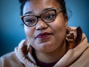 Close up of Brittany White, black woman with large ear rings, glasses in a sweater