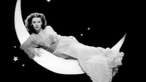 Hedy Lamarr, 1943, in a publicity shot for her film The Heavenly Body, laying across a sliver of the moon in 'space."