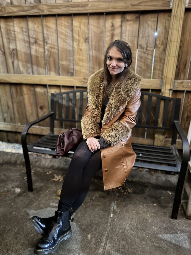 A woman sits on a bench outside. 