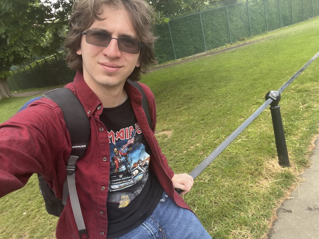 A man sits on a fence outside. 