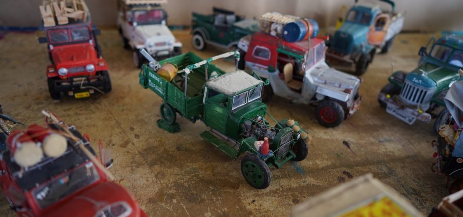 A group of highly detailed mini trucks, some packed for camping or moving. All, is various colors with heavy details