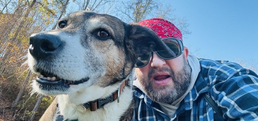 A man looks down into a camera with his dog.