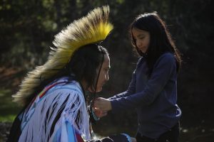 Delwin Fiddler Jr. with daughter Kassi Fiddler in Easton, PA. She is tying an Indian headdress under her fathers chin