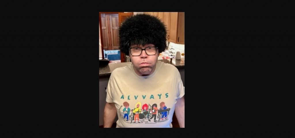 A picture of a man wearing a wig and an Alvvays t-shirt. 