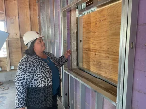 Cynthia Bonidie points to a window in what used to be a bar, but will become her office at the Homeward Bound shelter, as it was under construction in October 2024.