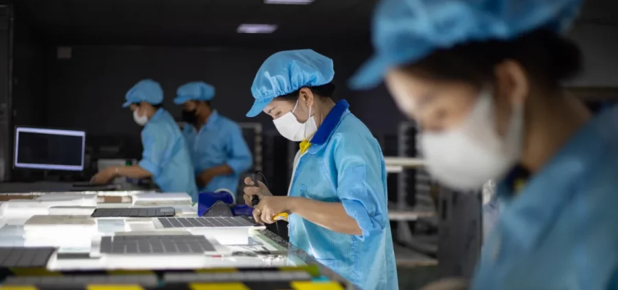 Rows of factory workers solder together solar cells at Red Sun Energy’s factory outside Ho Chi Minh City, Vietnam.