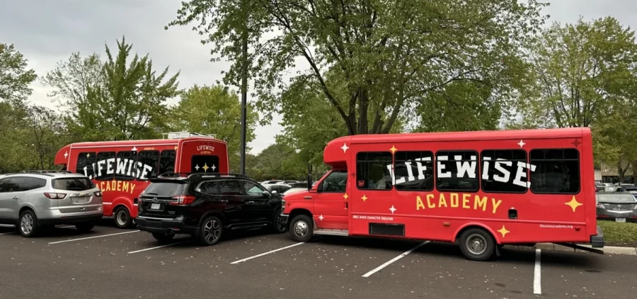 Two smaller LifeWise buses outside the Westerville Board of Education meeting.