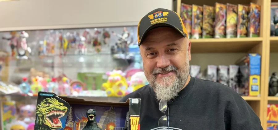 Vintage toy shop owner Rob Eldridge holds up a Godzilla action figure