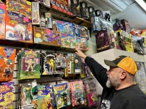 Rob Eldridge goes over his vintage toy collection on multiple shelves.